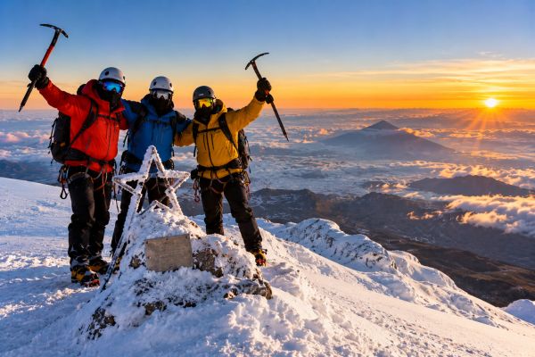 Mountaineers celebrating at Chimborazo's Estrella summit in Ecuador, surrounded by snow-covered Andean peaks, breathtaking sunrise views, and spectacular high-altitude landscapes.
