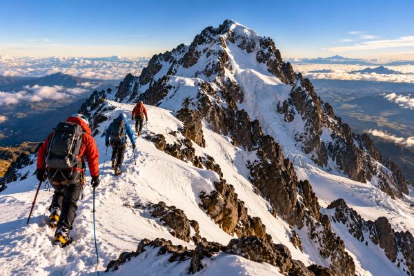 Mountaineers ascending Iliniza Norte (5,125 m) in Ecuador, navigating a snow-covered Andean ridge with breathtaking views of rugged volcanic peaks and spectacular high-altitude landscapes.