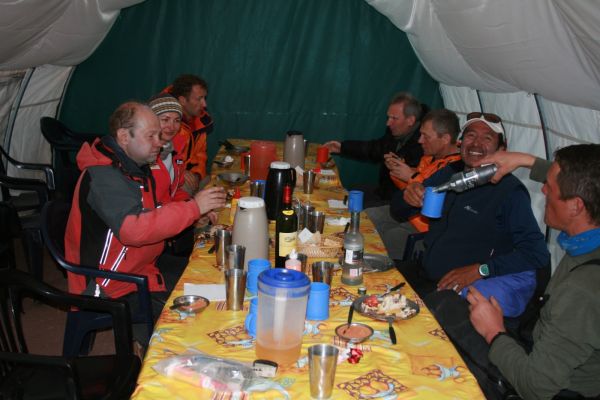 A group of climbers gathering around a long table inside a dining dome tent at Mount Aconcagua base camp in Mendoza, Argentina.