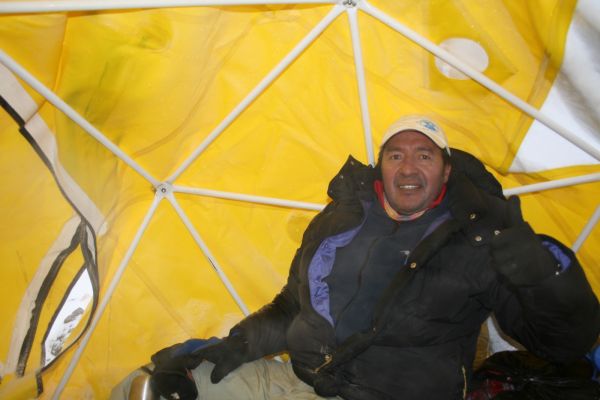 Authentic photo from inside Aconcagua base camp. A happy guide in a yellow geodesic tent gives a thumbs up before an Andes climbing expedition in Mendoza.