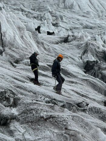 Climbers wearing helmets and harnesses navigate a steep, icy slope surrounded by dramatic glacier ice pinnacles on Cotopaxi Volcano, Ecuador.