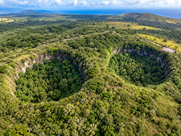 Spectacular aerial view of Los Gemelos (Twin Craters) in the highlands of Santa Cruz Island, Galapagos Islands, Ecuador, featuring impressive volcanic sinkholes surrounded by lush green forests, scenic walking trails, and the extraordinary natural landscapes of this iconic Galapagos destination.