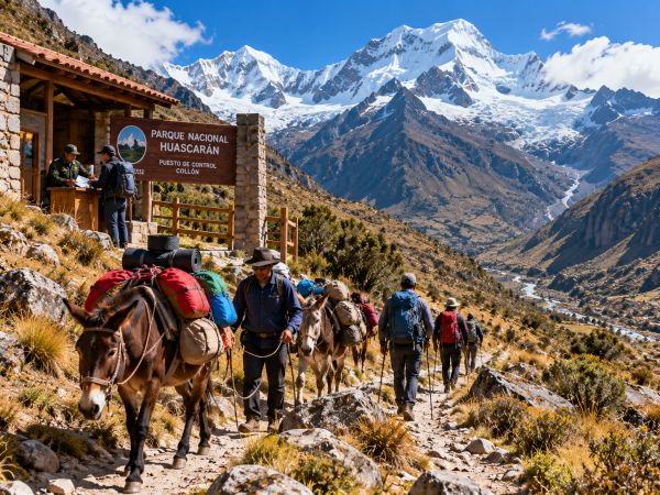 Mountaineers trekking from Collón village into the spectacular Ishinca Valley in Huascarán National Park, near Huaraz, Peru. Accompanied by local guides and pack mules carrying camping equipment and expedition supplies, hikers follow scenic high-altitude trails surrounded by towering snow-capped peaks, rugged Andean mountains, and breathtaking landscapes of the Cordillera Blanca on their way to Ishinca Base Camp.